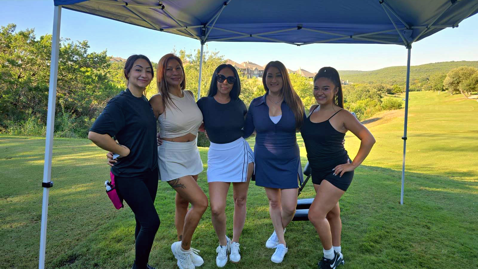 Five women who helped make the 2026 Golfing For Our Veterans tournament a success, smiling together under the tournament tent at Cedar Creek Golf Course, October 8, 2026